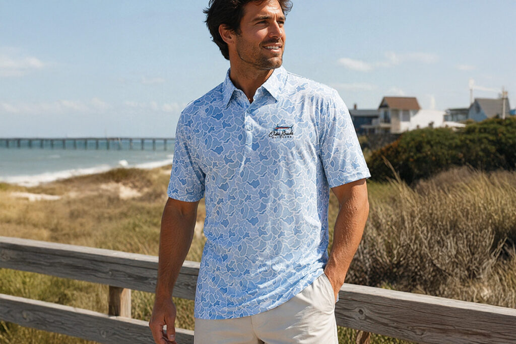 A man wearing a blue polo shirt and shorts stands on a wooden boardwalk